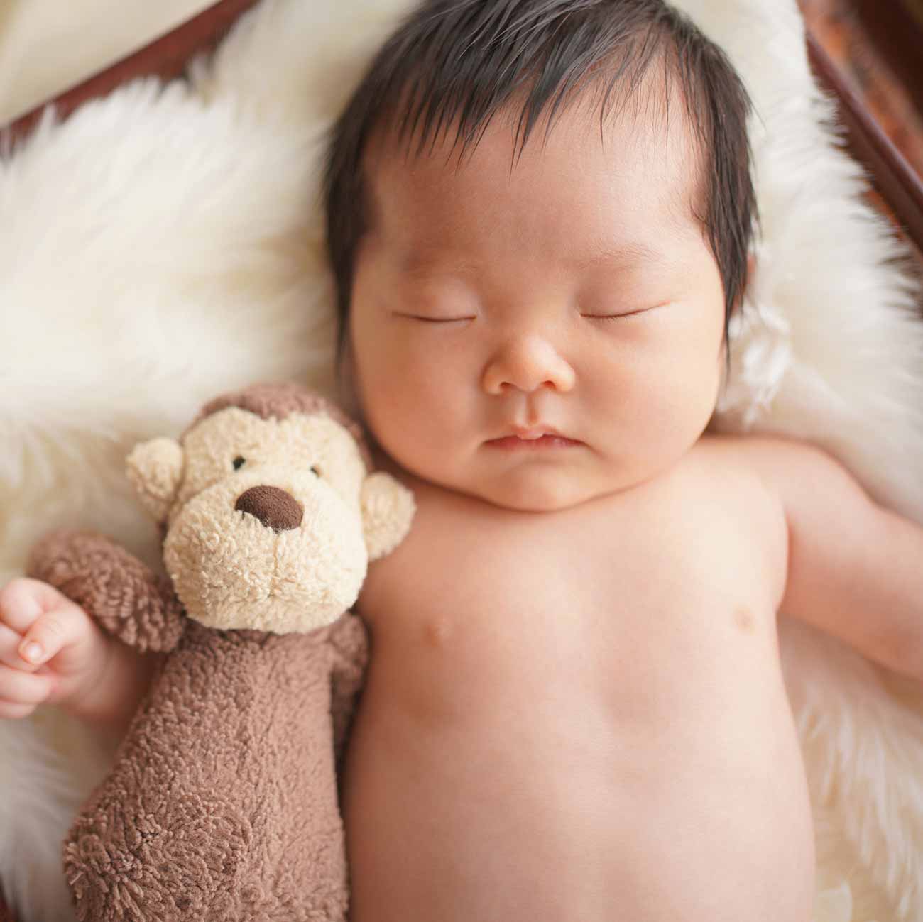 ぬいぐるみと一緒に眠っている赤ちゃんの写真
